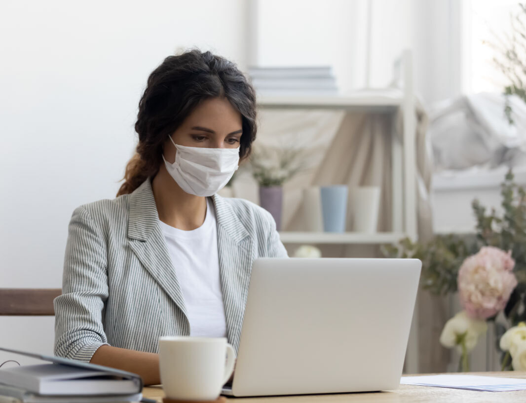 A woman wearing a non-surgical mask, safely translating at her computer.