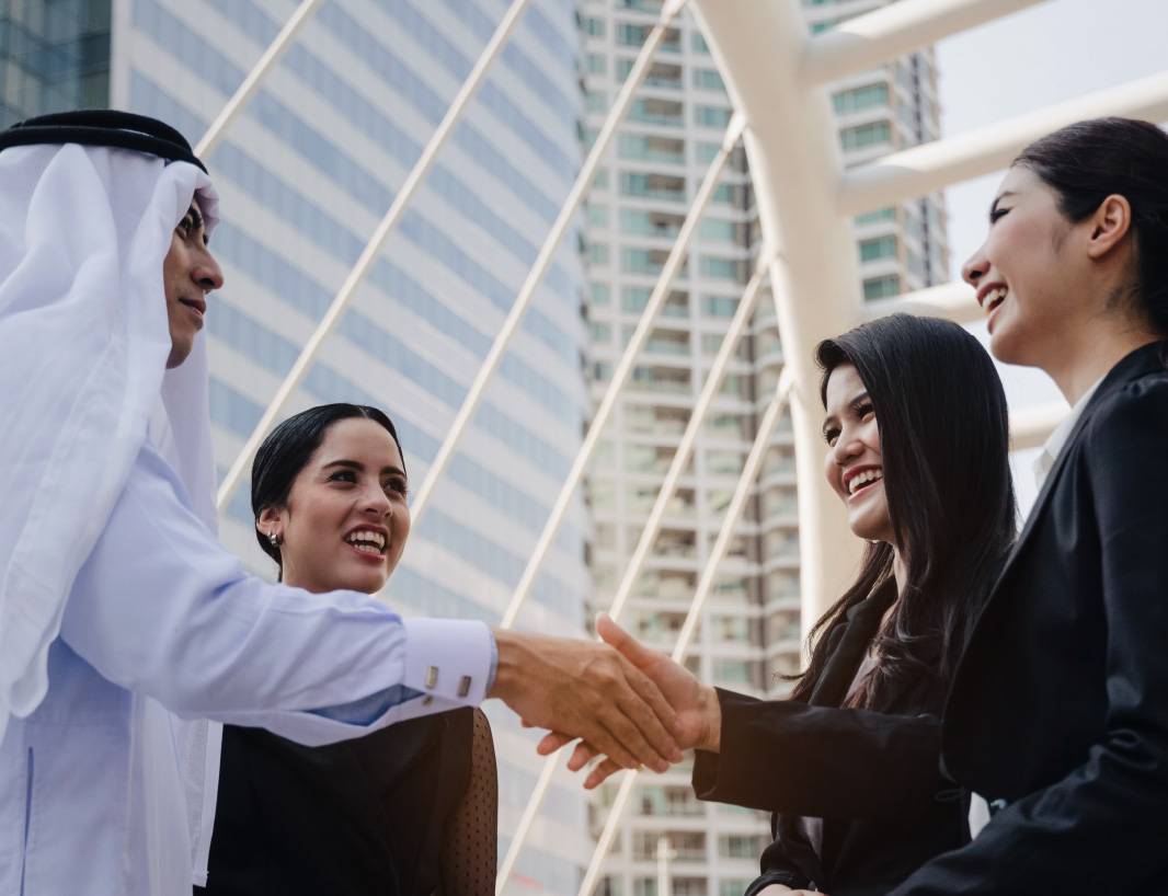 A diverse group of people from different language backgrounds speaking and shaking hands.